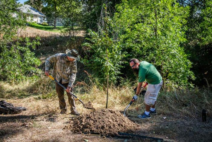 Two volunteers plant a new drought-tolerant tree. 