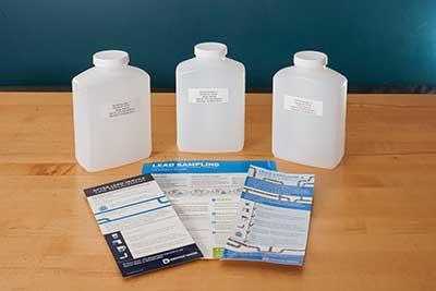3 white plastic bottles sit on a table with printed material.