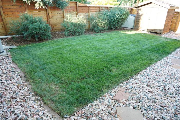 A square of green lawn surrounded by a rock border. 