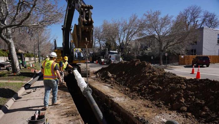 Crews lower a water main into the ground