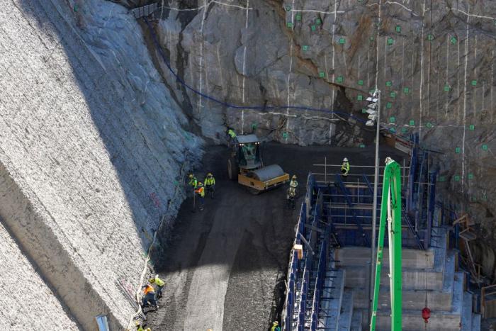 Machines working on the side of a concrete dam