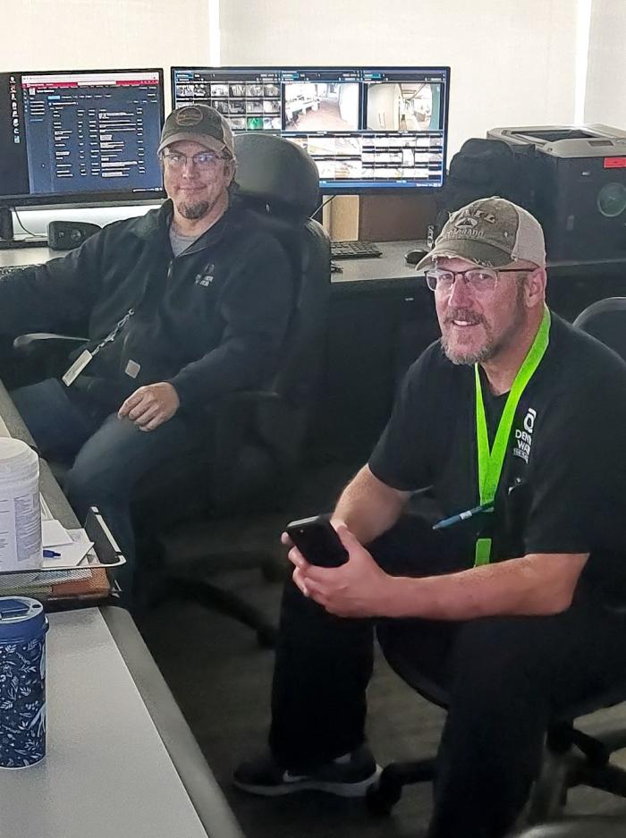 Two men sit near computers