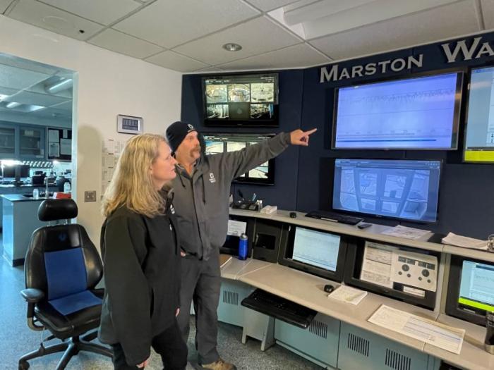 Two people look at a wall of monitors