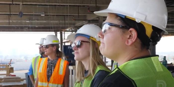 People wearing hard hats look out over a construction site