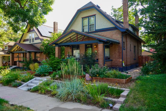 The front of a house, surrounded by colorful native landscape.