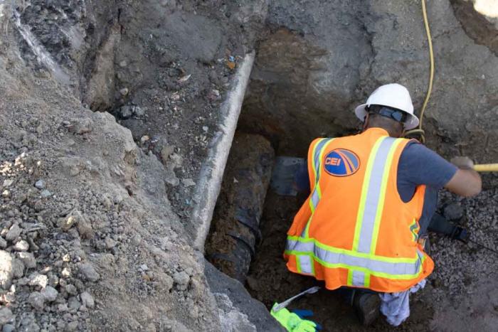 Man in orange safety vest works in a trench