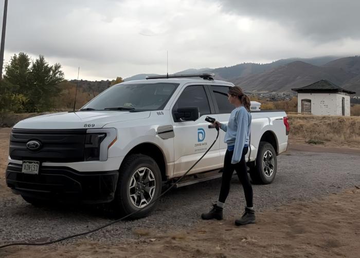 Woman plugs in a white electric truck