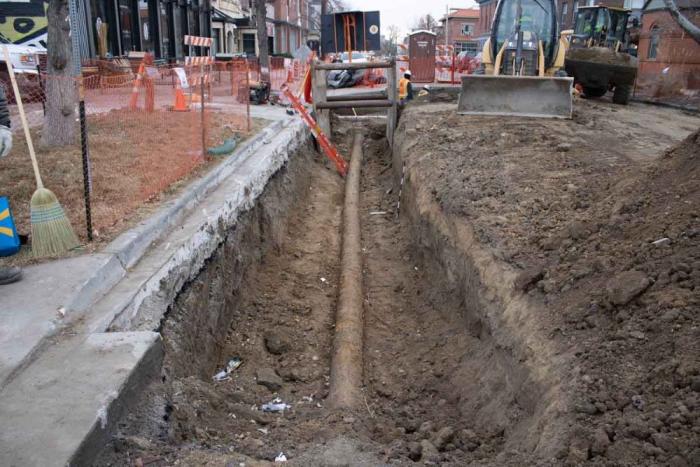 Street view of a pipe in the ground with dirt dug around it