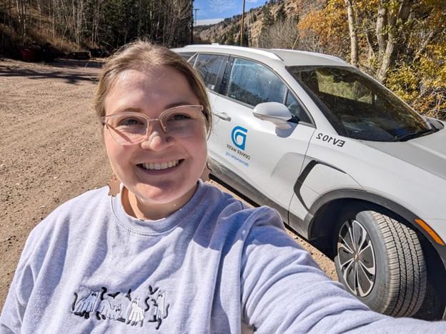 Woman takes a selfie next to a white electric SUV