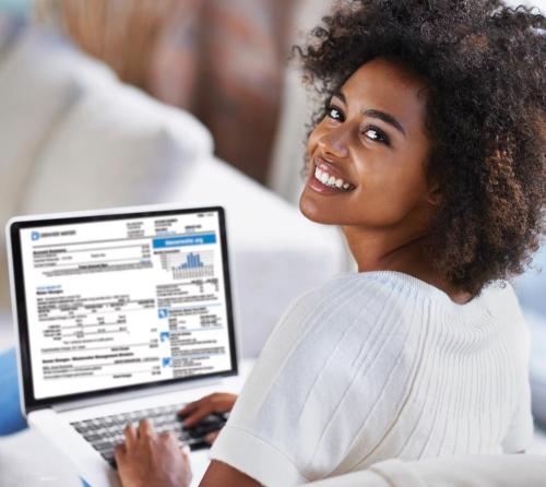 Woman is on her computer paying her Denver Water water bill. She's smiling as she looks over her should at the camera. 