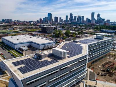 Solar panels on top of a building with the downtown Denver skyline in the distance.