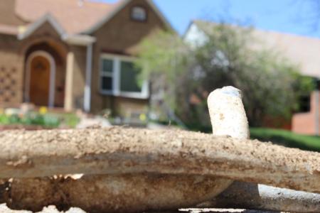 Lead pipe taken out of the ground sits on the sidewalk