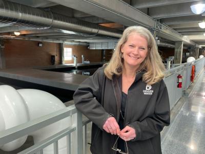 A woman stands in front of the interior of a water treatment plant