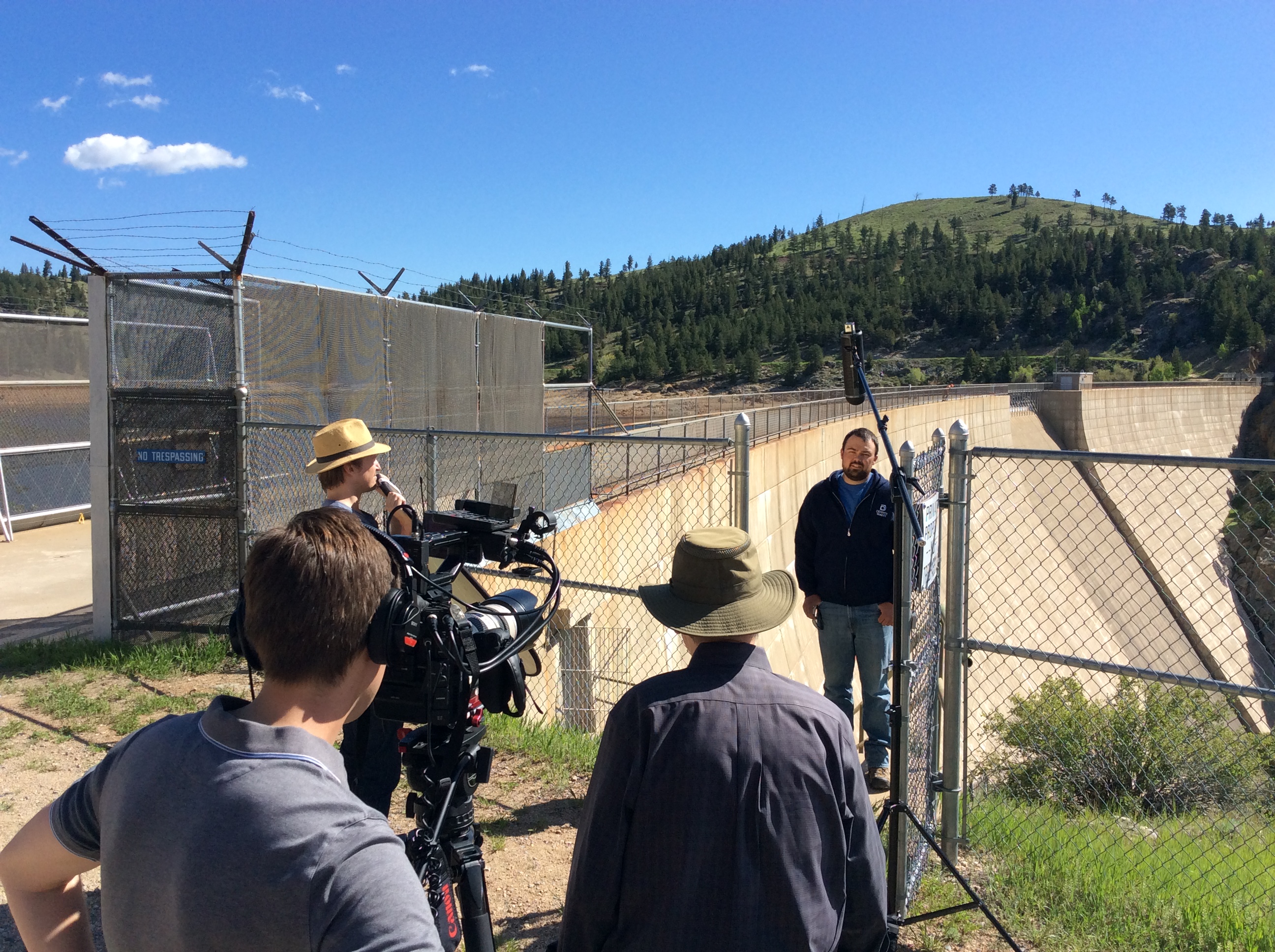 Pierre Goetz, Gross Reservoir hydro operator and caretaker, does an interview with the film crew from HaveyPro Cinema, (from left) Nathan Church, partner, editor and creative director, Zach Andrews (in hat on the left), assistant editor and camera operator, and Jim Havey (in hat on the right), owner, producer and director. 